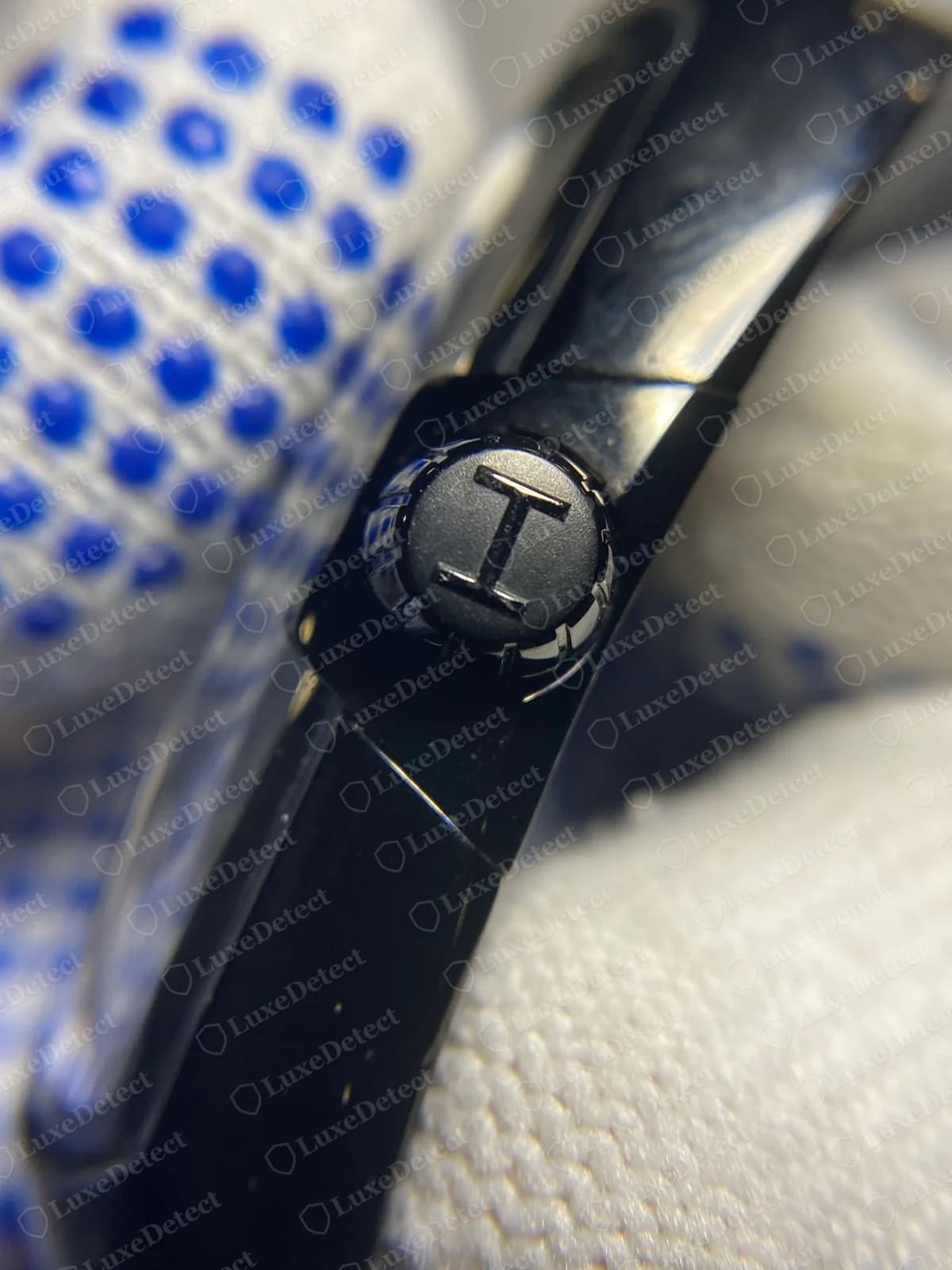 Close-up of the crown on a genuine black Hamilton Ventura, with a Hamilton H logo on the end and a ridged edge