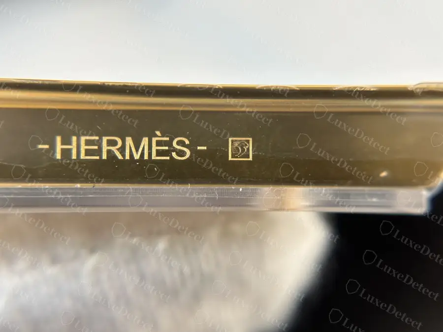 Top edge of a gold Constance H clasp: -HERMÈS- engraving followed by a small square hallmark