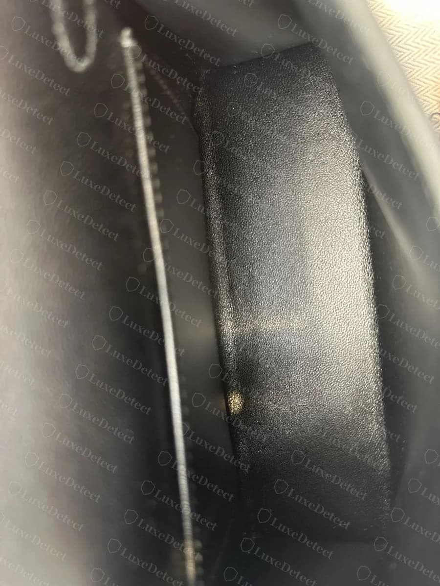 The same bag's strap-keeper interior in completely smooth, unscaled leather, no texture at all where the panel above shows clear alligator scales