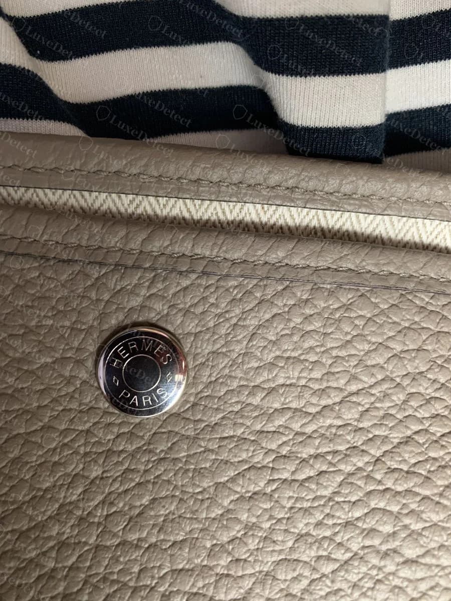 Genuine Hermès clou stud stamped "HERMÈS PARIS," set flush into the leather near the bag's opening