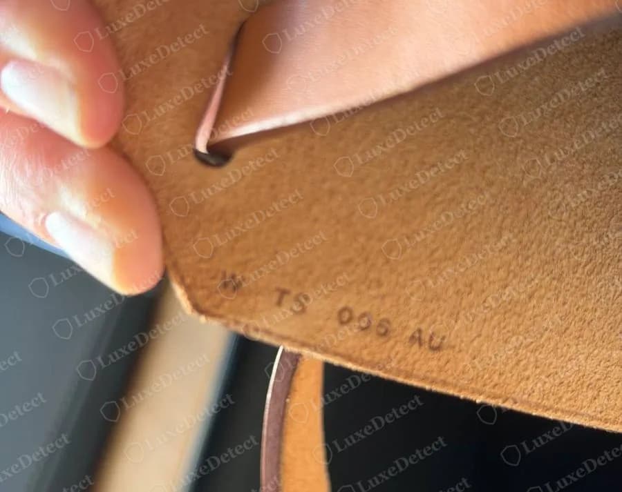 Underside of the tan flap on a genuine 2024 Herbag Zip, a line of small stamped characters beginning with W, the 2024 year letter