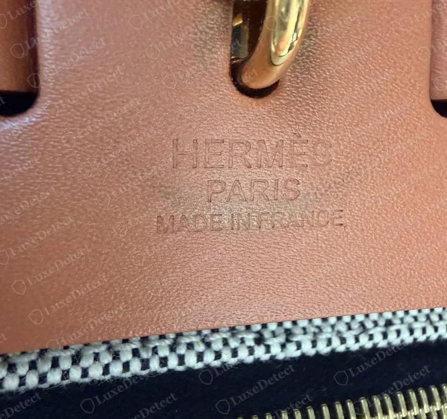 HERMÈS PARIS MADE IN FRANCE grabado en caliente en tres líneas en el frente de la solapa color tostado de un Herbag Zip original, bajo la correa del cierre