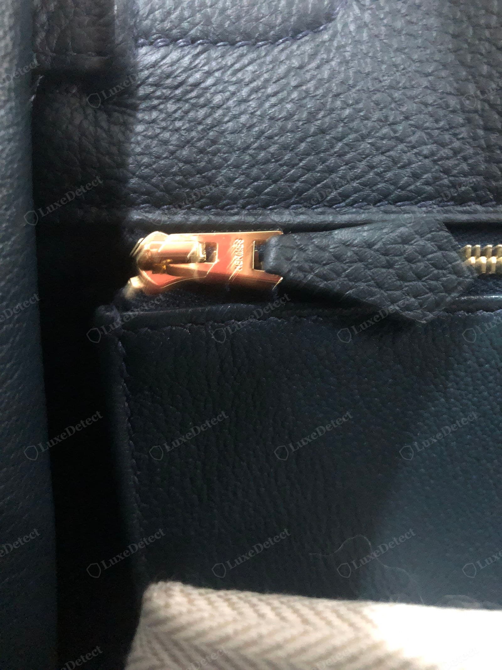 Genuine Hermès leather — navy Epsom with its fine, regular hobnail emboss and slight sheen, a rose-gold H-shaped zip pull engraved "HERMÈS", on a herringbone lining