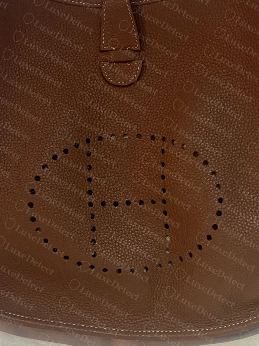 Perforated H on a counterfeit Evelyne, crossbar sitting visibly low within the oval and uneven hole spacing on the left upright