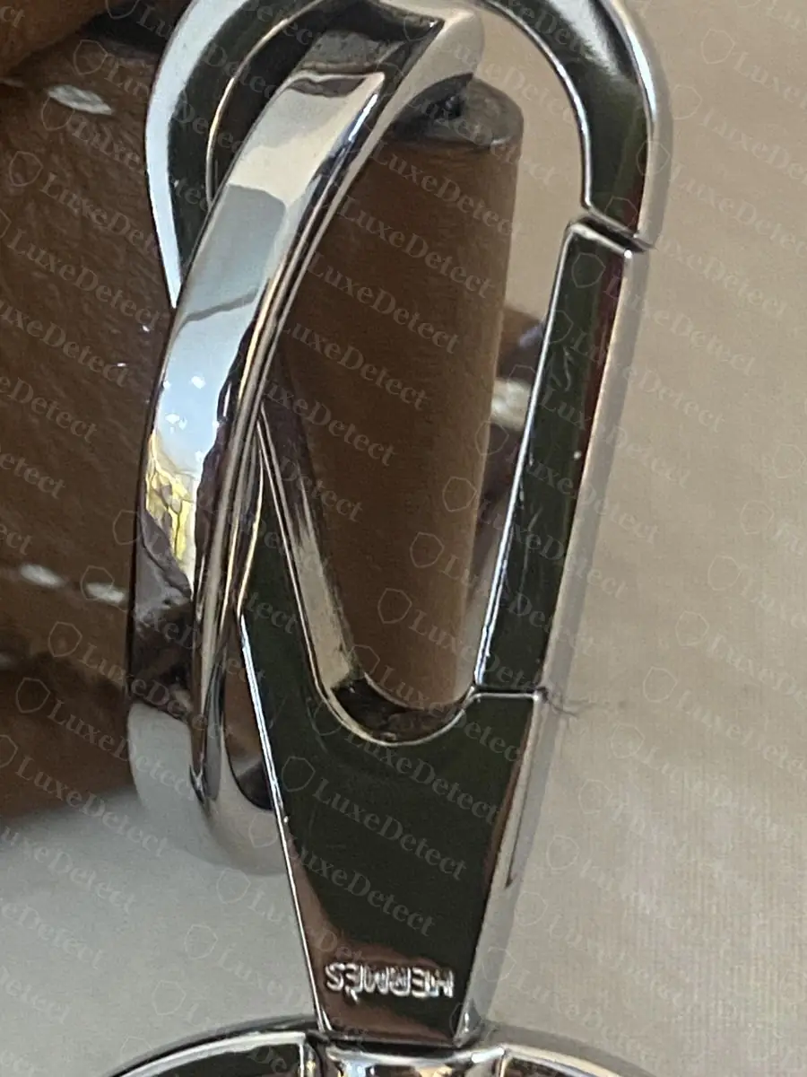 Snap hook on a counterfeit Evelyne, silver hardware with a similarly engraved HERMÈS mark but a visibly less crisp casting line at the pivot