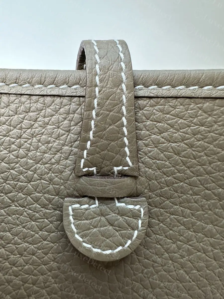 Authentic strap keeper tab, saddle stitching following the half-moon curve evenly with no drift from the leather edge