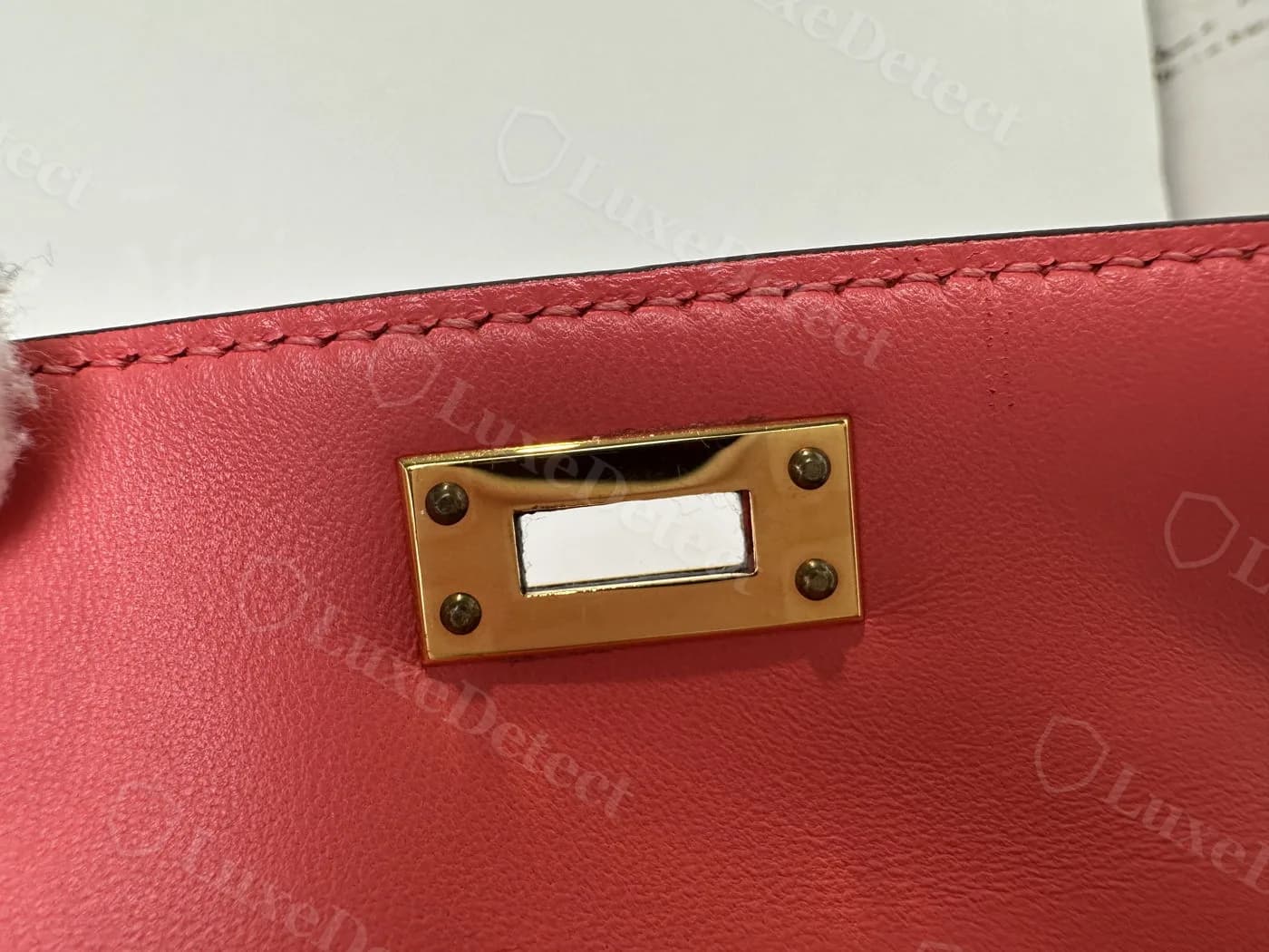 Counterfeit Kelly turn-lock plate with no engraving visible, the space where HERMÈS-PARIS should appear left blank