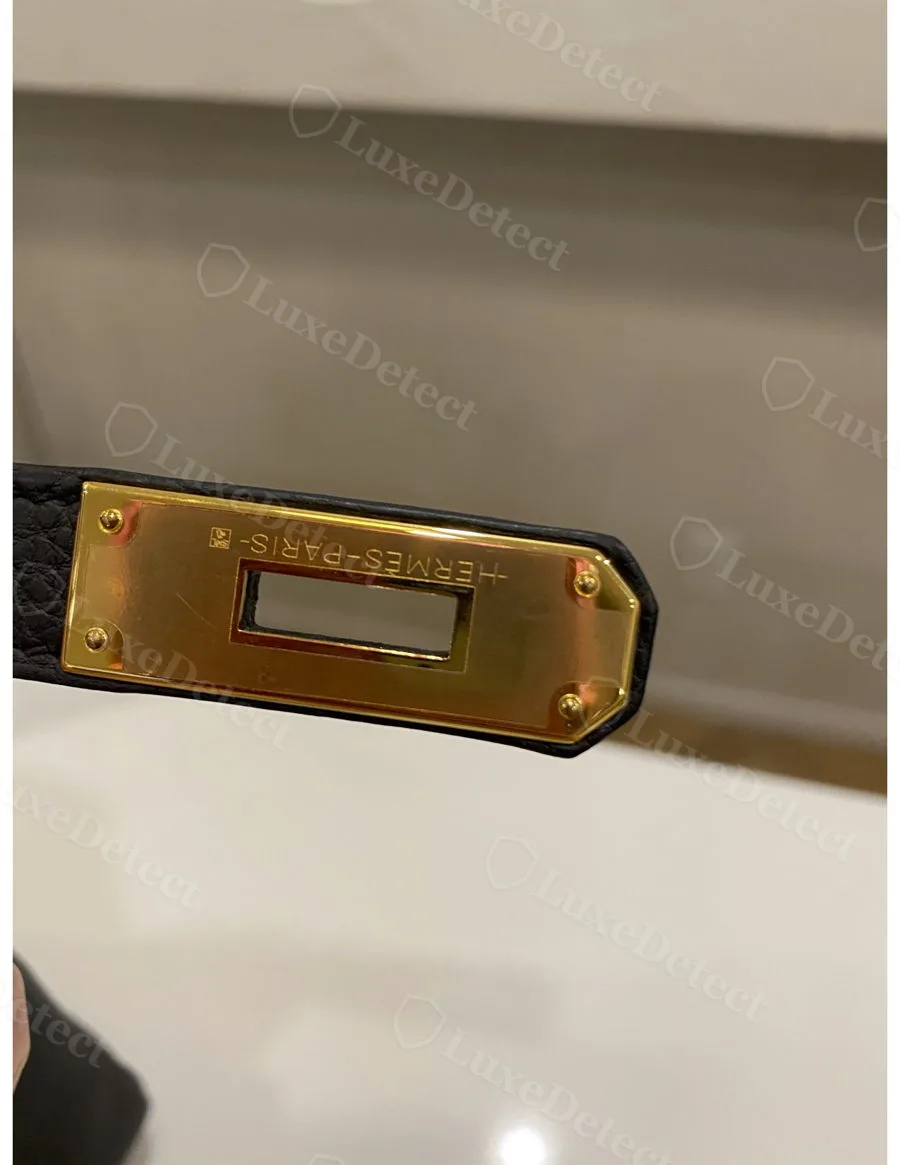 Genuine turn-lock plate on a black Kelly, HERMÈS-PARIS engraved with even depth and clean rivet seating