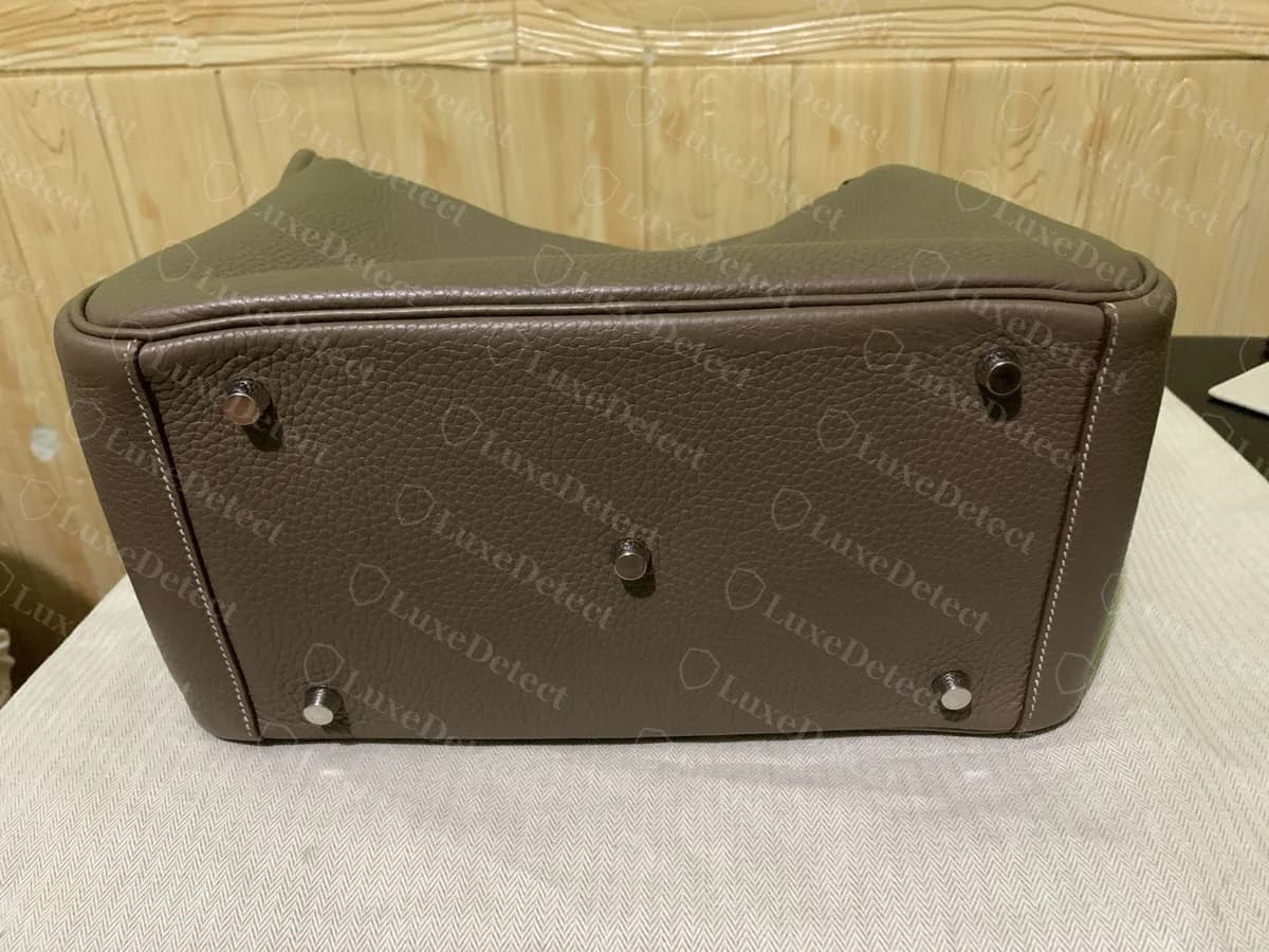 Genuine Hermès Lindy base, showing five symmetrically placed metal feet stitched into reinforced leather tabs, level and evenly spaced