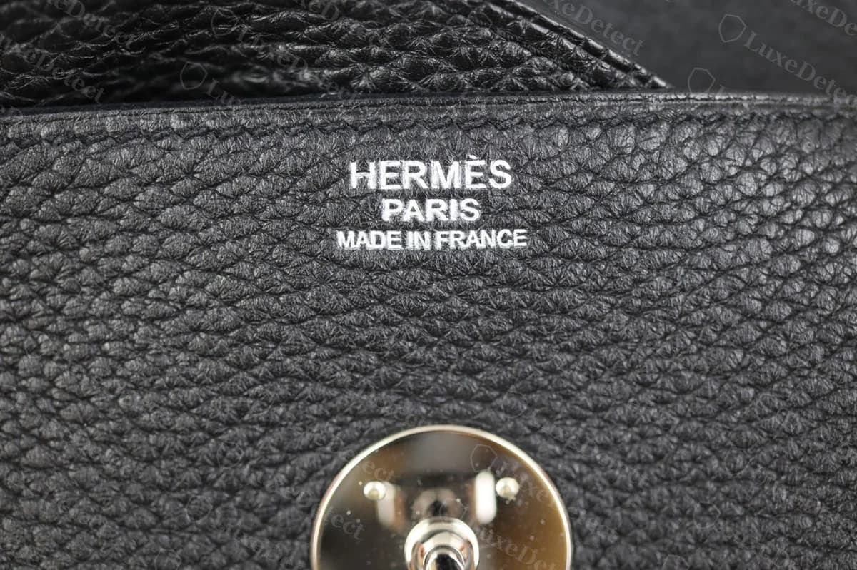 Genuine Hermès Lindy blind stamp and strap swivel clasp on black Clemence leather with palladium hardware, showing the same crisp stamping and clean clasp fit