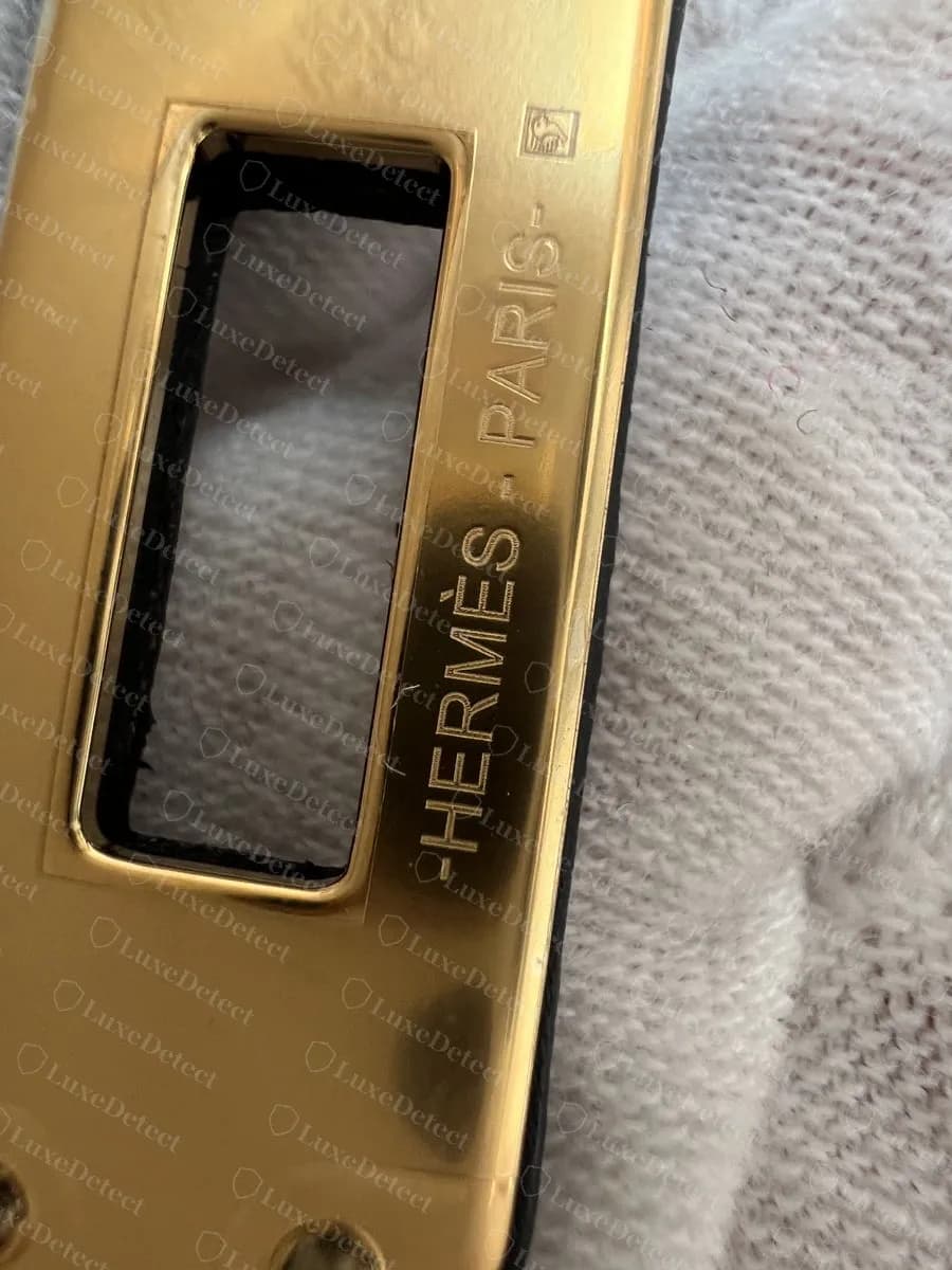 Genuine Kelly Pochette turn-lock plate in gold-tone hardware, HERMÈS-PARIS engraved along the long edge of the opening with a small square hallmark