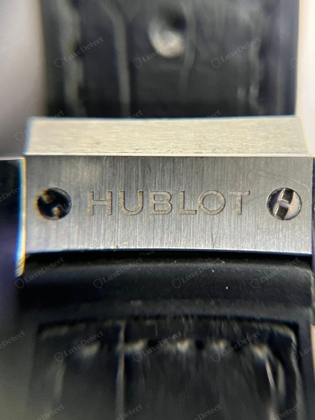 Genuine Hublot deployant clasp — "HUBLOT" engraved deep and evenly spaced, with an H-head screw at each end