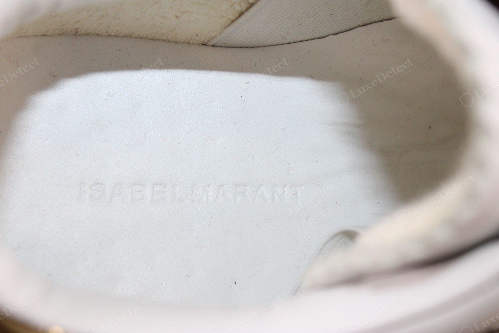 Counterfeit Isabel Marant branding — a sneaker insole blind-embossed "ISABELMARANT" with the words nearly run together, the letter spacing cramped and the stamp shallow and uneven