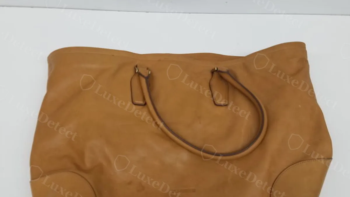 Full exterior silhouette of an authenticated Jil Sander hobo bag: soft, slouchy tan leather body, dual leather handles with plain metal loop connectors, minimal hardware