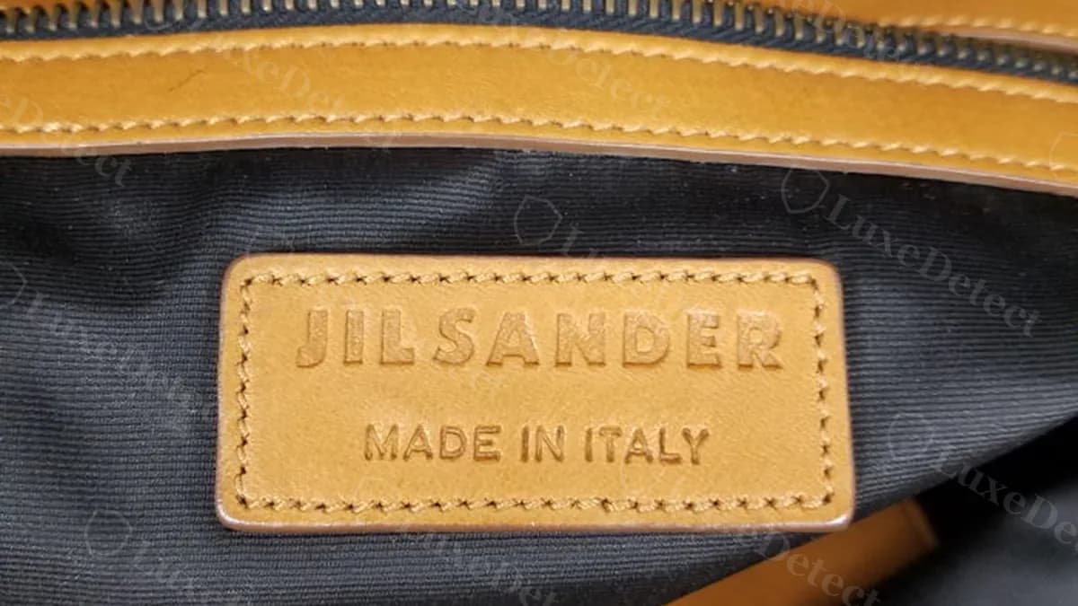 Authentic Jil Sander hobo bag interior, leather tag reading "JIL SANDER" and "MADE IN ITALY" stitched inside the zip pocket