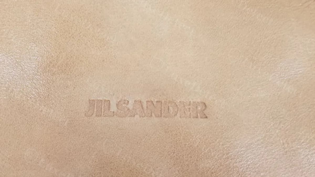 Authentic Jil Sander hobo bag, exterior front panel showing the debossed "JILSANDER" wordmark as one unbroken word pressed directly into the leather