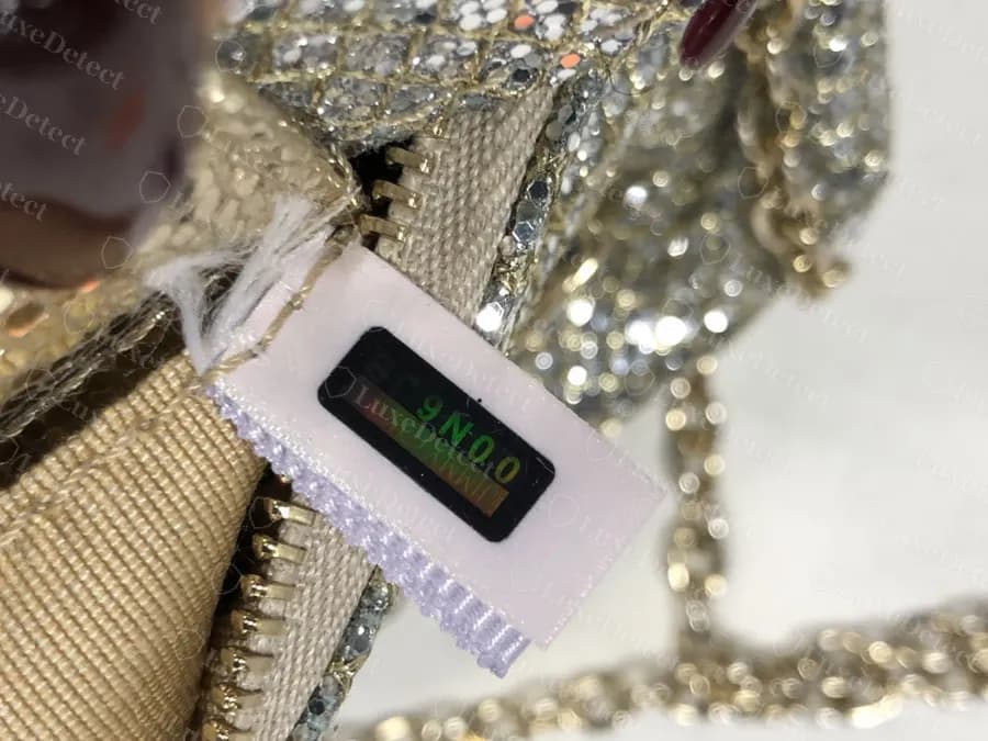 Un clutch falso de purpurina con una cinta y un panel holográfico, así que la presencia de una etiqueta no despeja un bolso