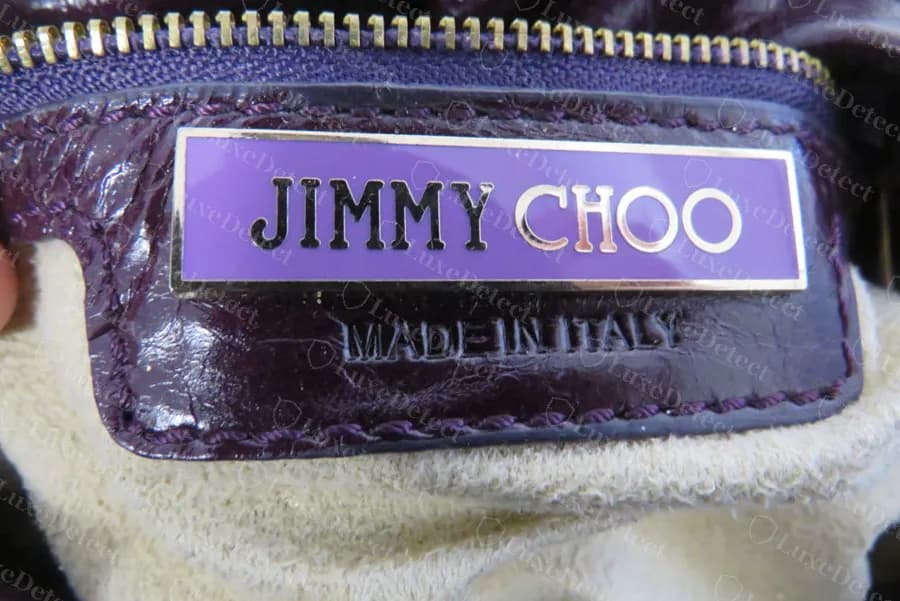 Genuine Jimmy Choo interior plaque in lilac enamel with dark capitals, stitched to a purple crinkled-leather tab with MADE IN ITALY struck beneath it
