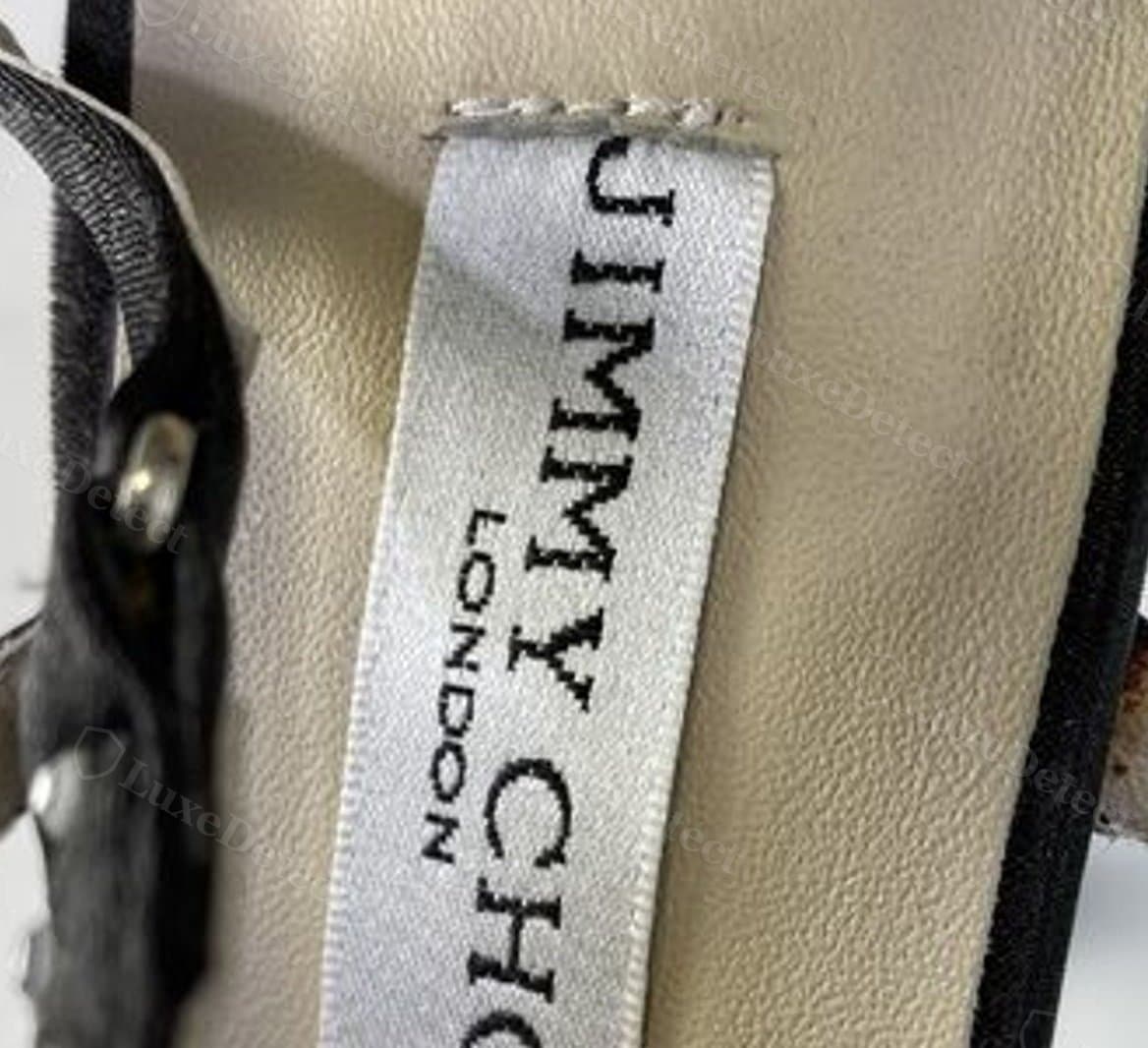 Étiquette de semelle intérieure Jimmy Choo contrefaite : la couture n'est visible que sous la forme d'un court zigzag sur le bord supérieur, les côtés et le bas de l'étiquette n'étant pas cousus à la semelle
