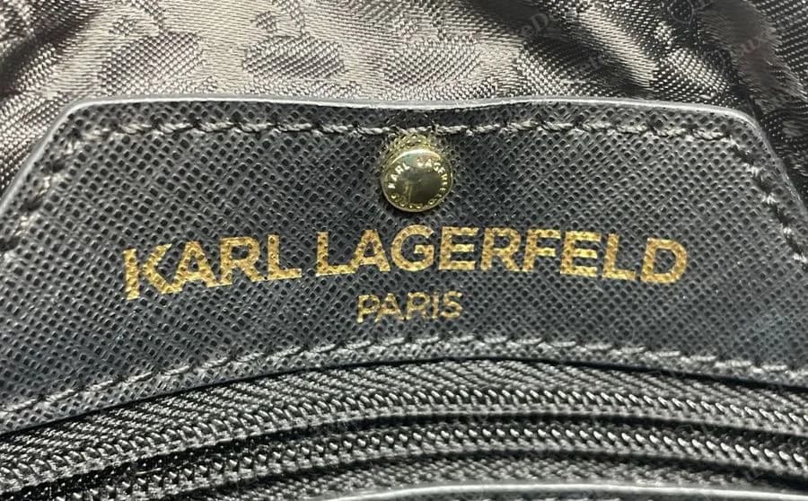 Genuine Karl Lagerfeld interior plate in black saffiano leather, stitched to the lining, with a gold-tone snap above gold foil lettering reading KARL LAGERFELD and PARIS beneath