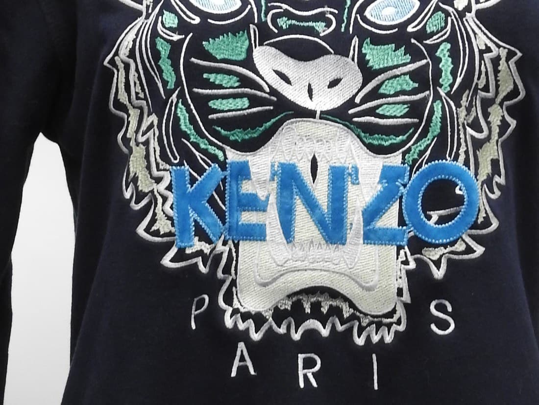 Genuine Kenzo Tiger embroidery — the tiger face resolves into clean, distinct color-blocked panels in navy, teal, white, and grey, with a raised satin-stitch texture and the KENZO wordmark as a clean applique patch across the muzzle