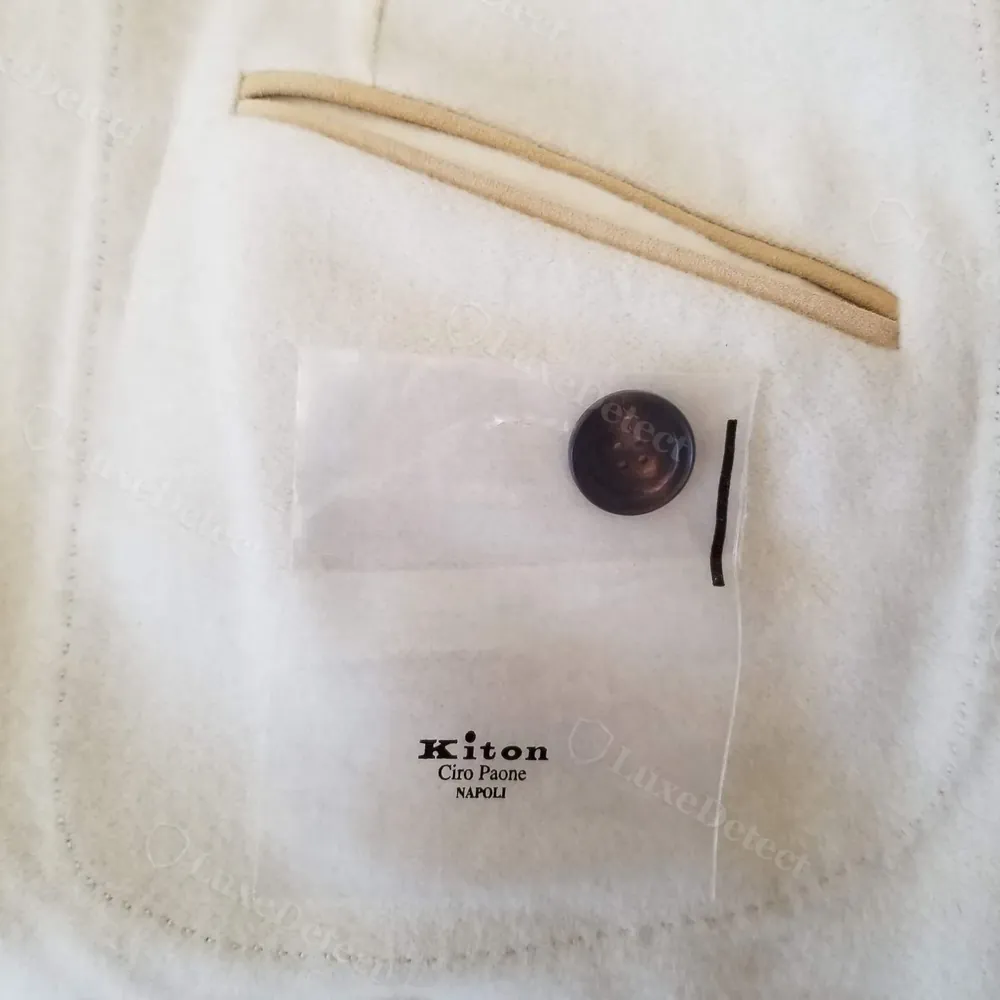 Interior chest pocket on a Kiton jacket holding a sealed spare-button sachet printed Kiton, Ciro Paone, Napoli