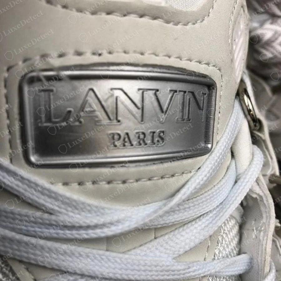 Genuine Lanvin Curb tongue plaque, a raised rectangular metallic plate reading LANVIN PARIS, with a flat-woven lace passing in front
