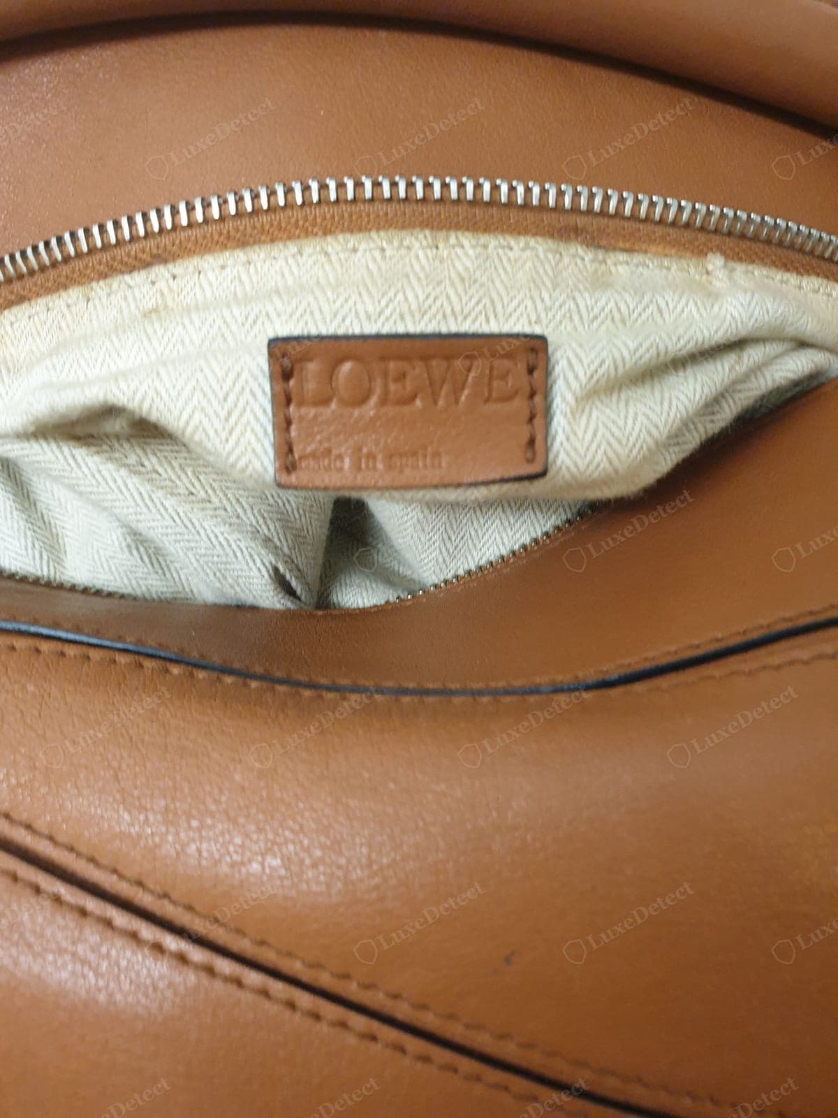Counterfeit Loewe Puzzle interior — inconsistent or thin suede nap, visible adhesive, a crooked or wrong-font label