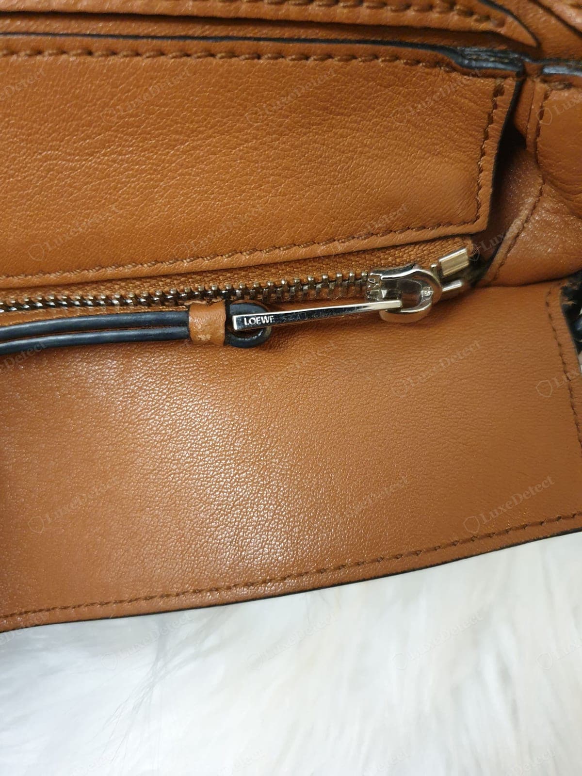 Counterfeit Loewe Puzzle zip-stopper — a shallow, blobby, or wrong-font engraving, or no engraving at all