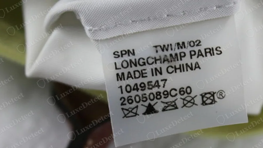 Genuine Longchamp Le Pliage interior tag, upper-case lines reading a code, LONGCHAMP PARIS, MADE IN CHINA, a seven-digit number, a ten-digit line and five wash symbols