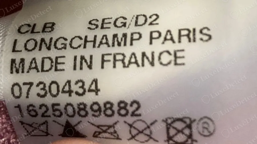 Étiquette intérieure d'un Longchamp Le Pliage authentique fabriqué en France, avec un code, LONGCHAMP PARIS, MADE IN FRANCE, un numéro de produit et des symboles d'entretien