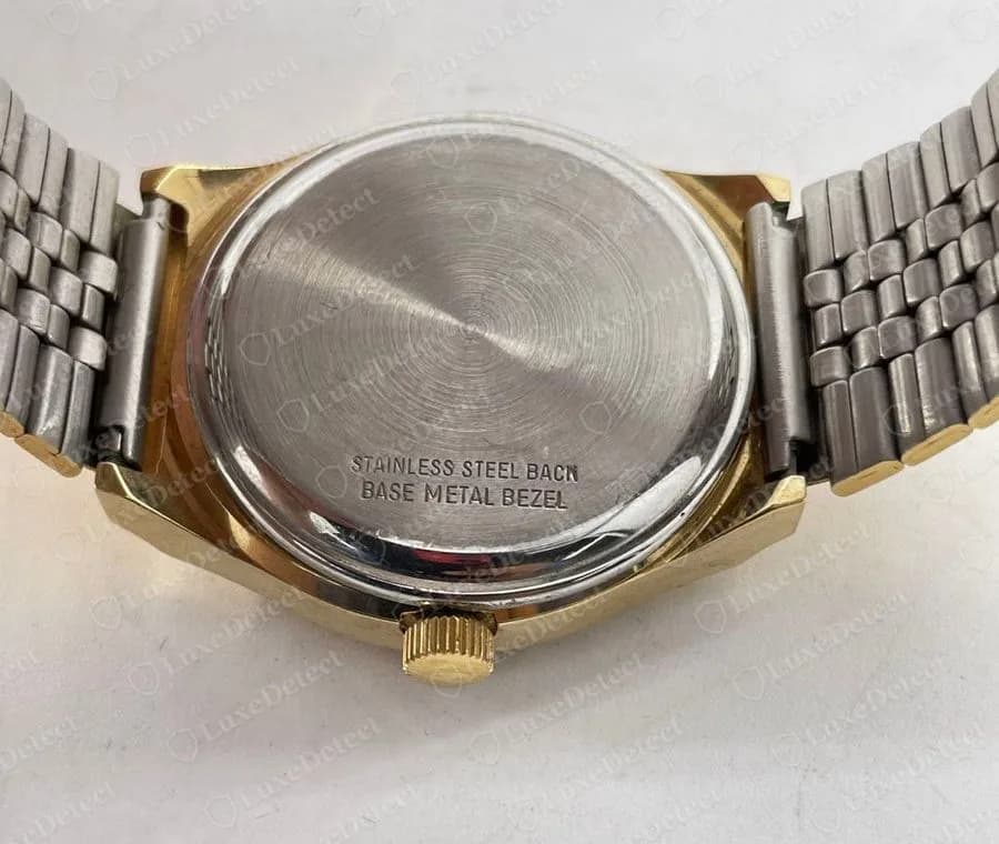 Back of a genuine gold-tone Longines quartz watch printed STAINLESS STEEL BACK and BASE METAL BEZEL on a plain stainless steel caseback