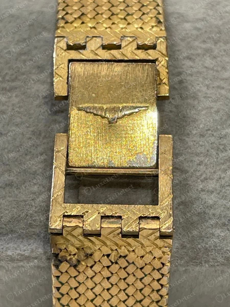 Genuine gold-tone Longines mesh bracelet clasp opened to show a winged hourglass stamped on the inner leaf