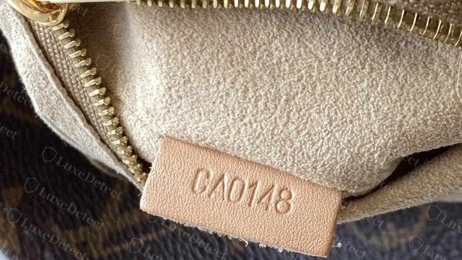 Genuine Artsy with the date code CA0148 on a small leather tab beside the zip pocket