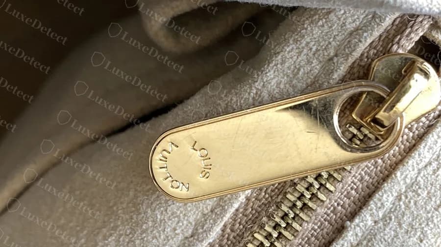 Genuine Artsy interior zipper pull with LOUIS VUITTON engraved in a circle on a flat gold pull