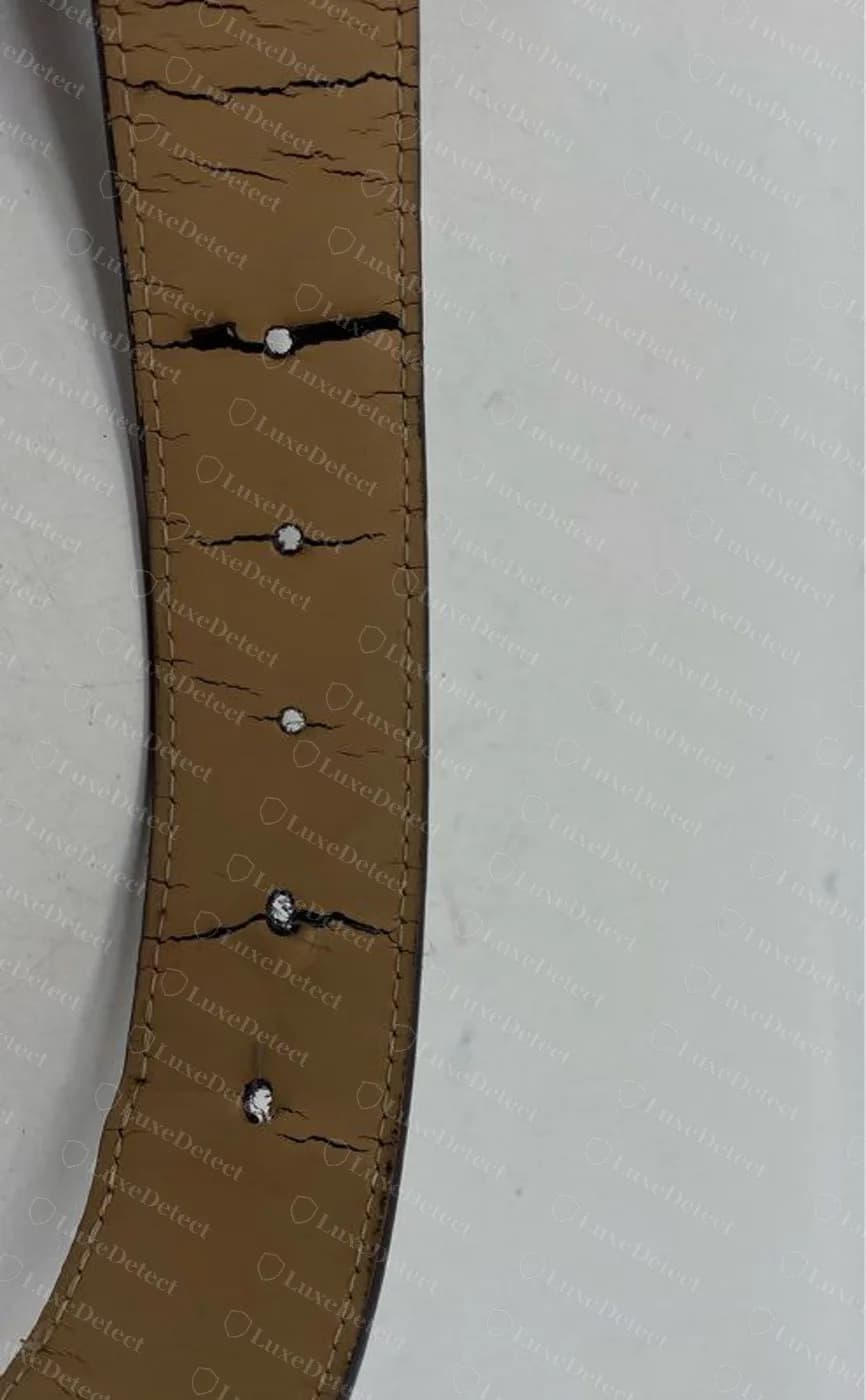 Counterfeit LV belt underside: the surface coating has crazed across the whole strap and split open around the punched holes