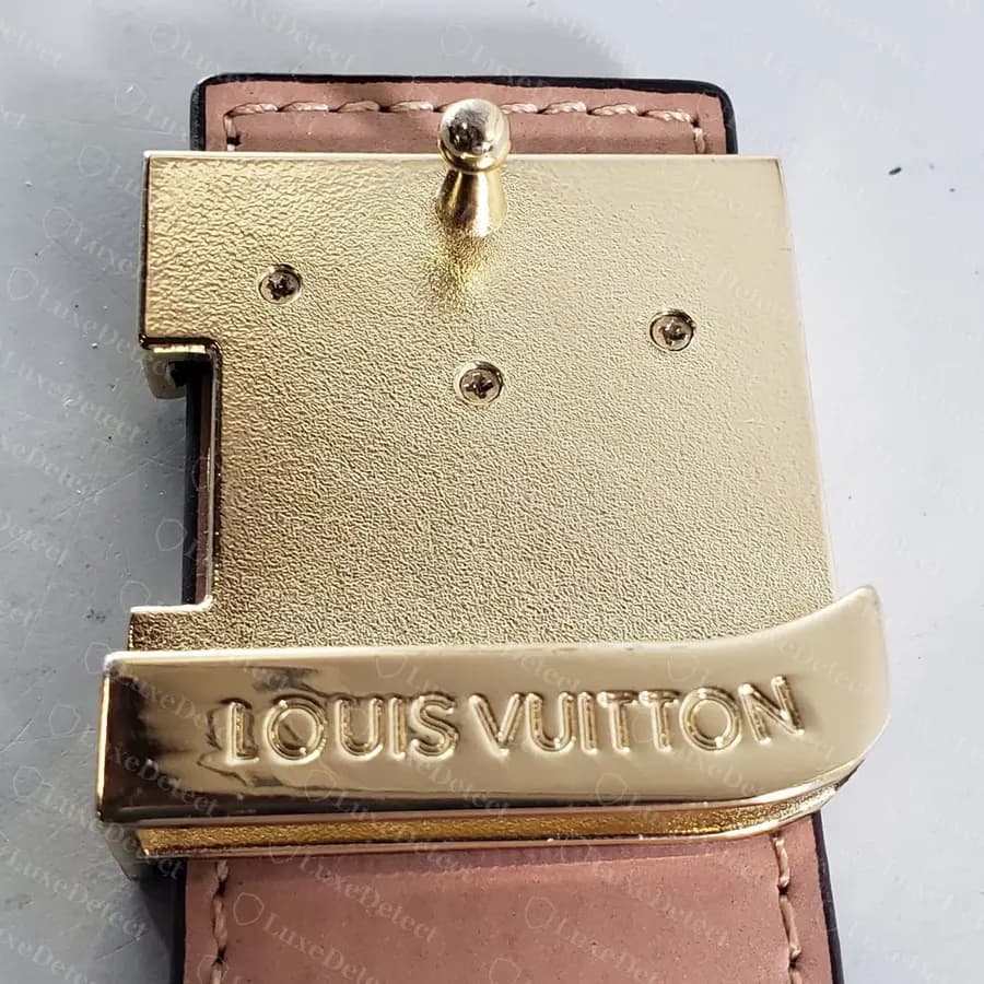 Counterfeit LV Initiales buckle back: grainy gold back plate with cross-head screws, and LOUIS VUITTON embossed in heavy letters across the keeper bar
