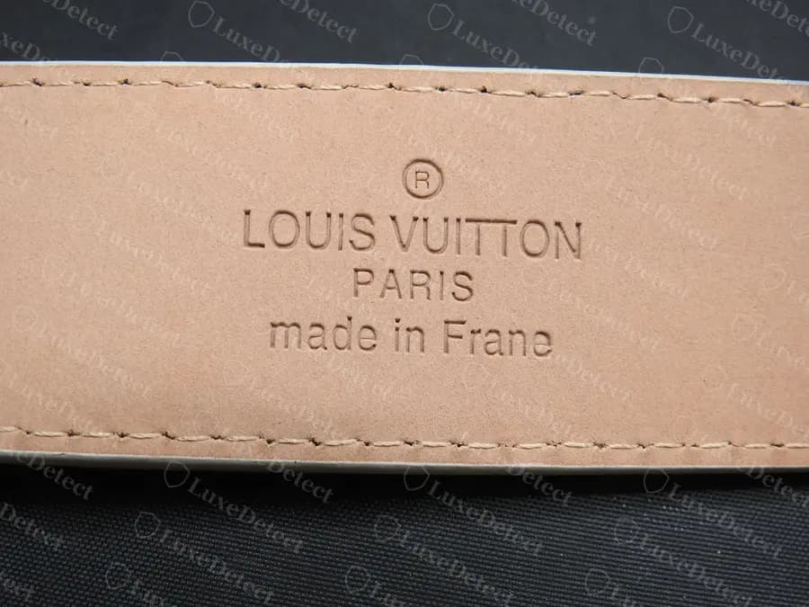 Counterfeit LV belt heat stamp reading made in Frane, a misspelling of France, on smooth pinkish leather