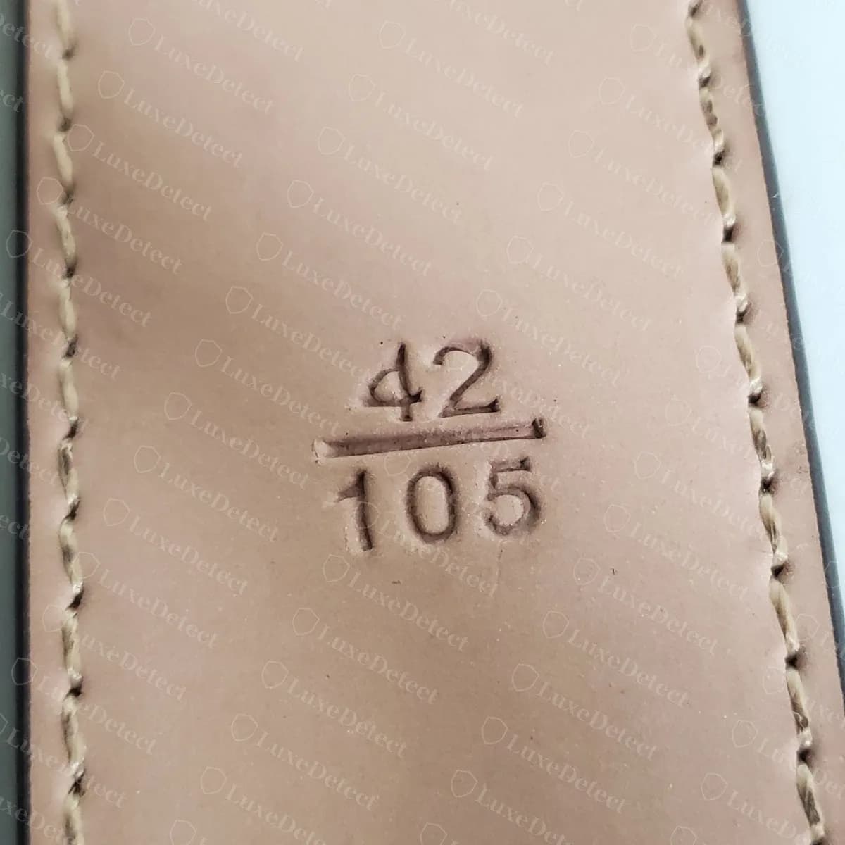 Counterfeit LV belt size stamp reading 42 over 105, with inches on top and centimetres below, deeply pressed into pinkish leather