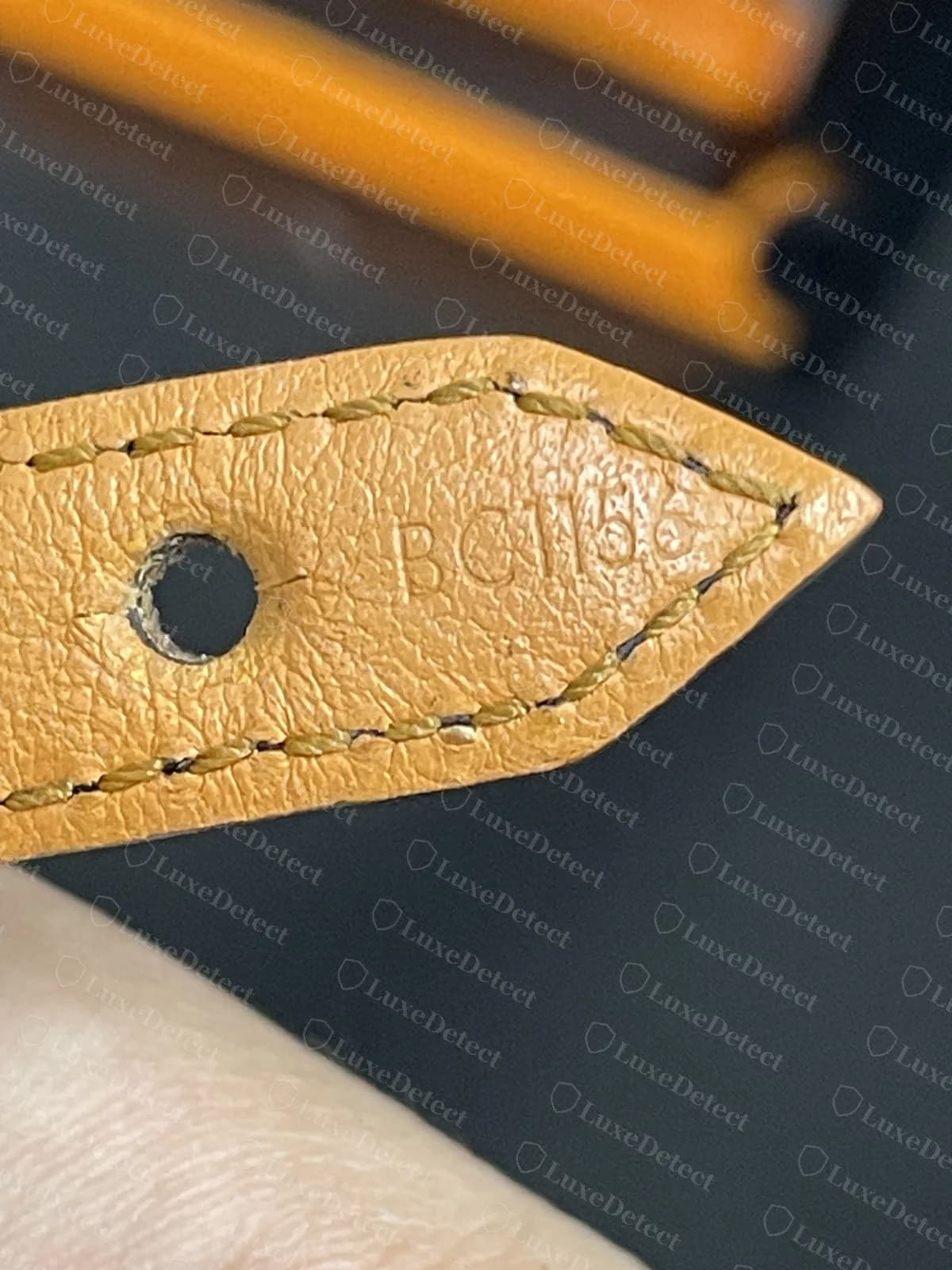 Authentic leather bracelet tab with a heat-stamped date code pressed into the leather beside the buckle hole