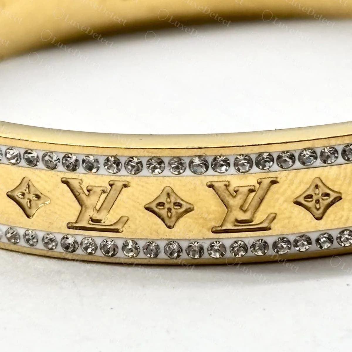 Counterfeit hinged bangle with a row of rhinestones along each edge and enlarged LV initials, a design we could not match to any Louis Vuitton reference