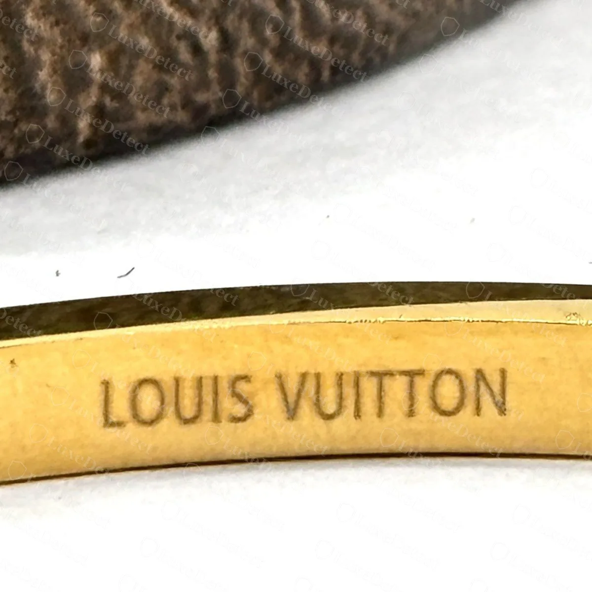 Counterfeit gold-tone bangle with only LOUIS VUITTON inside the band, no registered mark, no PARIS and no reference stamp