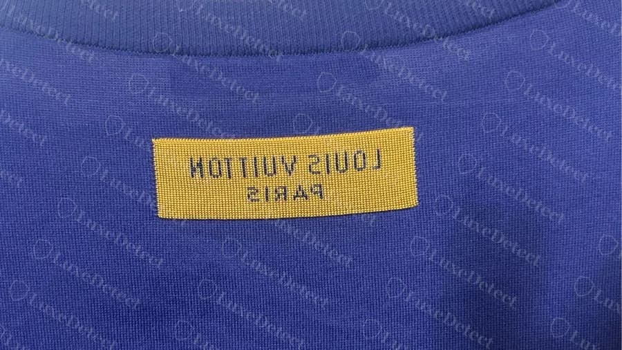 Parche tejido LOUIS VUITTON PARIS en espejo dentro de la parte trasera del cuello de una camiseta azul Louis Vuitton original
