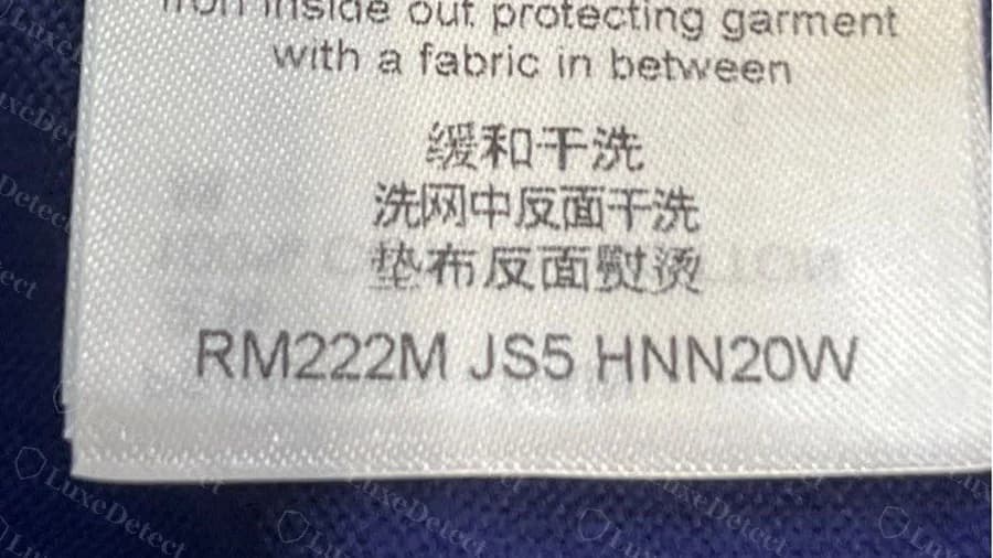 Etichetta di manutenzione originale Louis Vuitton su una maglietta blu, che termina con il codice di manutenzione RM222M JS5 HNN20W