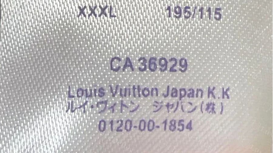 Otra etiqueta de camiseta Louis Vuitton falsa que imprime Louis Vuitton Japan K.K en mayúsculas y minúsculas, con CA 36929 arriba y el nombre de la empresa en japonés abajo