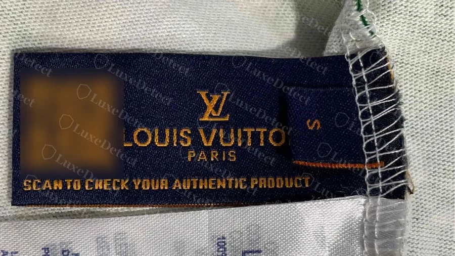 Etiqueta del cuello de una camiseta Louis Vuitton falsa con un código QR (difuminado) junto a LOUIS VUITTON PARIS y las palabras SCAN TO CHECK YOUR AUTHENTIC PRODUCT