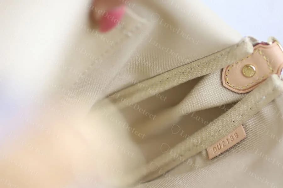 Genuine Louis Vuitton date code stamped into a small leather tab at the interior seam near the strap ring, two letters and four digits in even, consistently struck lettering