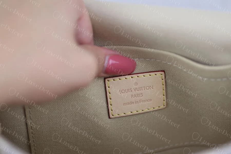 Genuine interior leather patch reading LOUIS VUITTON, PARIS, made in France, heat-debossed with yellow contrast stitching around the border
