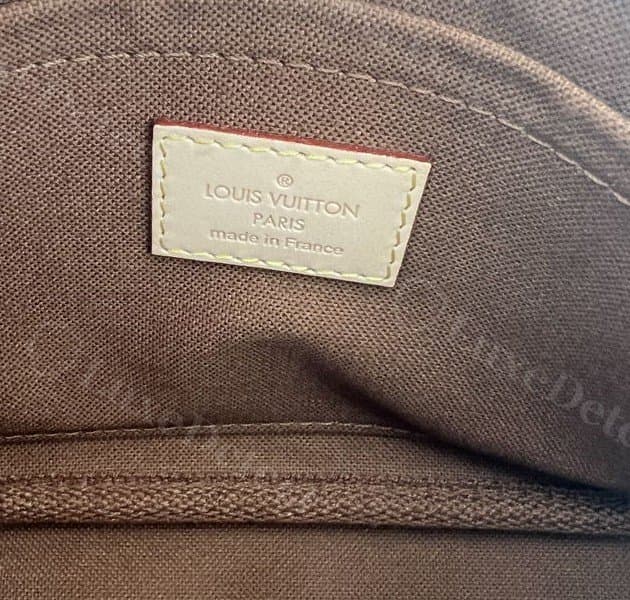 Etiqueta interior de piel LV en la pochette grande de una Multi Pochette original: grabado más claro, cosida en una lengüeta rectangular delgada sobre el forro oscuro