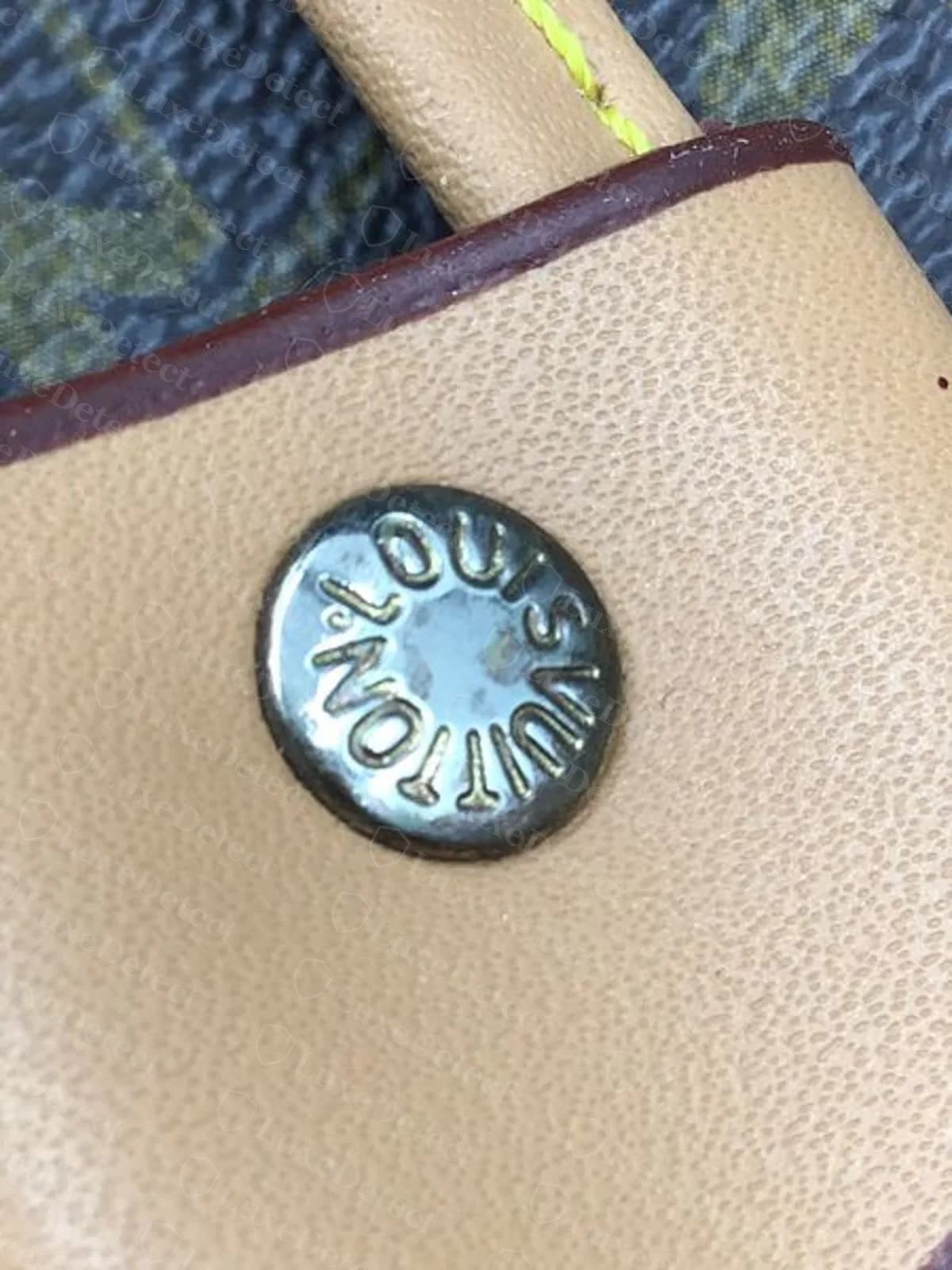 Fake Petit Noé rivet, part of the "LOUIS VUITTON" text mirrored backward around the circle. This defect repeated across four unrelated fake submissions.